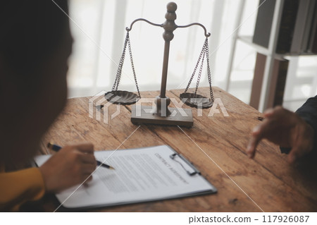 Business and lawyers discussing contract papers with brass scale on desk in office. Law, legal services, advice, justice and law concept picture with film grain effect 117926087
