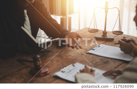 Business and lawyers discussing contract papers with brass scale on desk in office. Law, legal services, advice, justice and law concept picture with film grain effect 117926090