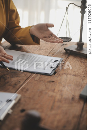 Business and lawyers discussing contract papers with brass scale on desk in office. Law, legal services, advice, justice and law concept picture with film grain effect Business and lawyers discussing contract papers with brass scale on desk in office. Law, legal services, advice, justice and law concept picture with film grain effect 117926096