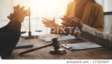 Business and lawyers discussing contract papers with brass scale on desk in office. Law, legal services, advice, justice and law concept picture with film grain effect Business and lawyers discussing contract papers with brass scale on desk in office. Law, legal services, advice, justice and law concept picture with film grain effect 117926097