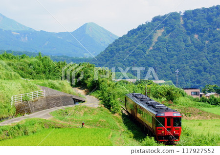 The Aso Express, a Kiha 185 series train running with the Aso mountains in the background 117927552
