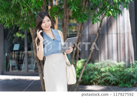 Businesswoman holding a tablet device in an office district 117927592