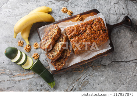 Vegan pasrty Banana Zucchini Bread with walnuts and dark chocolate closeup on the wooden board. Horizontal top view Vegan pasrty Banana Zucchini Bread with walnuts and dark chocolate closeup on the wooden board. Horizontal top view 117927875