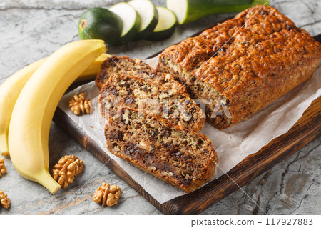 Freshly baked gluten free zucchini banana bread with walnuts and dark chocolate close-up on wooden board. Horizontal 117927883