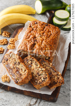 Banana Zucchini Bread with the addition of walnuts and dark chocolate closeup on the wooden board. Vertical 117927885