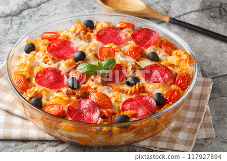 Pasta casserole with cheese, minced meat, salami sausage, peppers and olives with marinara sauce close-up in a glass baking dish. Horizontal Pasta casserole with cheese, minced meat, salami sausage, peppers and olives with marinara sauce close-up in a glass baking dish. Horizontal 117927894