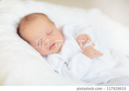 Little baby on white bed 117928610