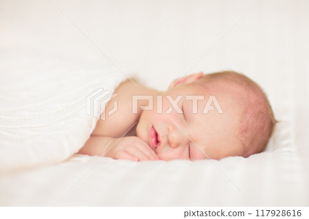 Little baby on white bed 117928616