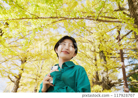 Young woman photographing autumn leaves Young woman photographing autumn leaves 117928707