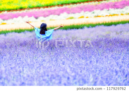 A flower field covering a hill and a woman 117929762