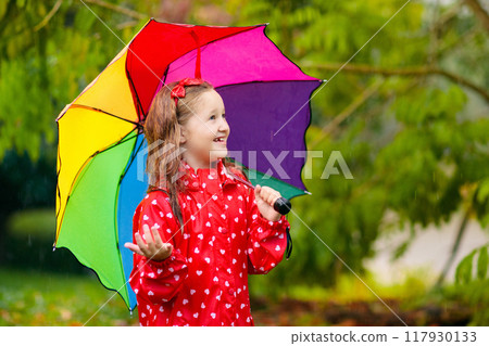 Kid with umbrella playing in summer rain. 117930133