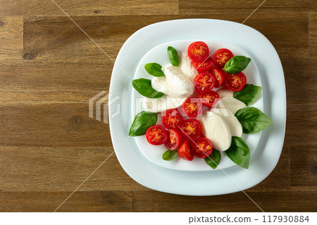 Mozzarella with basil and cherry tomatoes on a wooden table. 117930884