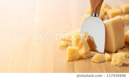 Hard cheese and knife on a oak cutting board. Hard cheese and knife on a oak cutting board. 117930896