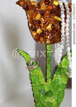 A beautiful necklace and a stunning ring are displayed on a vivid green flower 117931275