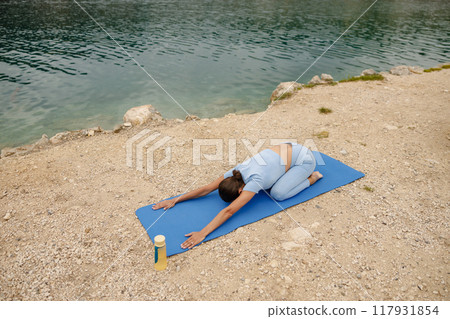 Engaging in a Relaxing Yoga Pose by the Serene Waters Edge to Achieve Inner Peace Engaging in a Relaxing Yoga Pose by the Serene Waters Edge to Achieve Inner Peace 117931854