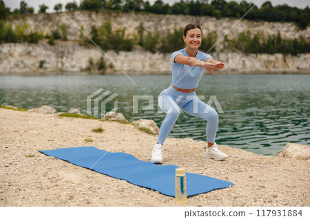A Woman Engaging in Exercise Activities Outdoors by the Beautiful Lake in Nature 117931884