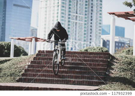Woman free rider riding bike going down city stairs 117932399