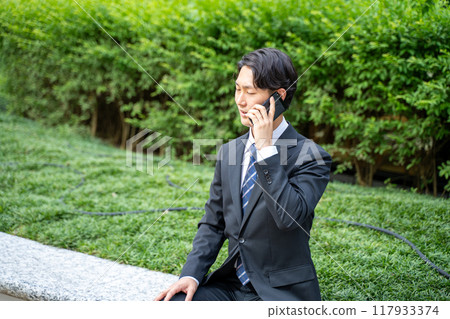 一位在路上透過智慧型手機溝通的商人 一位在路上透過智慧型手機溝通的商人 117933374