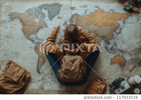 Young woman planning trip sitting on world map Young woman planning trip sitting on world map 117933538