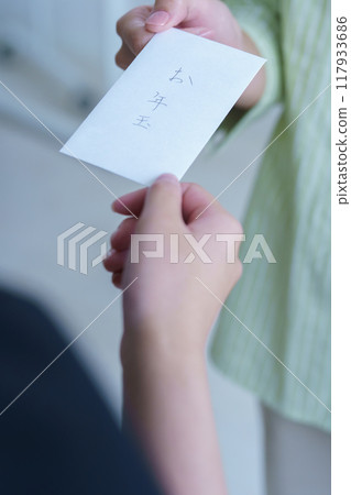 A young woman giving a makeshift otoshidama as a tip 117933686