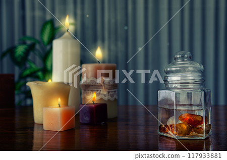 Soulful crystal elixir scene: Carnelian-infused water in glass container, surrounded by meditative candle glow. Soulful crystal elixir scene: Carnelian-infused water in glass container, surrounded by meditative candle glow. 117933881