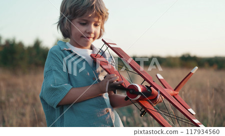 Curious 5 years old preschool child boy plays craft wooden retro styled airplane 117934560