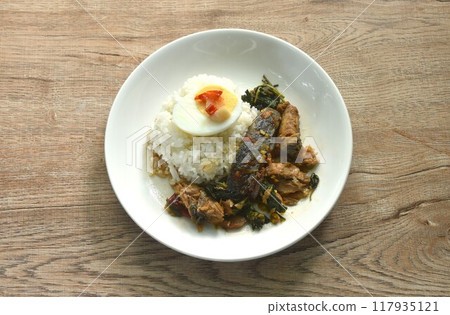 spicy str fried slice mackerel with chili and basil on rice topping boiled egg dressing chili garlic fish sauce in plate 117935121