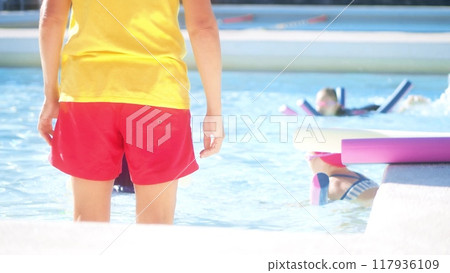 Unknown female swimming instructor teaches swimming to little kids in outdoor pool 117936109