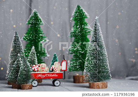 Merry Christmas and Happy New Year greeting card. Gingerbread men and lollipops in a cart with Christmas trees and copy space 117936196