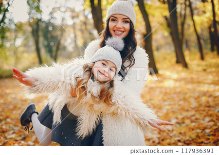 Beautiful mother with daughter. Family in a autumn park. Golden autumn Beautiful mother with daughter. Family in a autumn park. Golden autumn 117936391