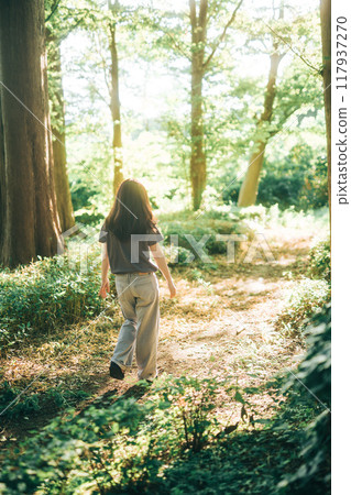 一個女人在森林裡散步,陽光透過樹林 一個女人在森林裡散步,陽光透過樹林 117937270