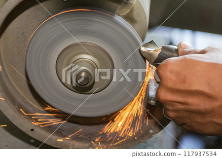 Close up scene the operator manual regrind the drill tool with sparking light. 117937534