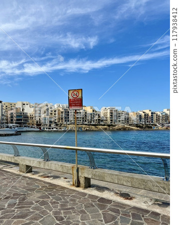 View of the promenade in Marsalforn Bay  (Salt Pans) at Gozo, Malta at sunny day with some clouds 117938412