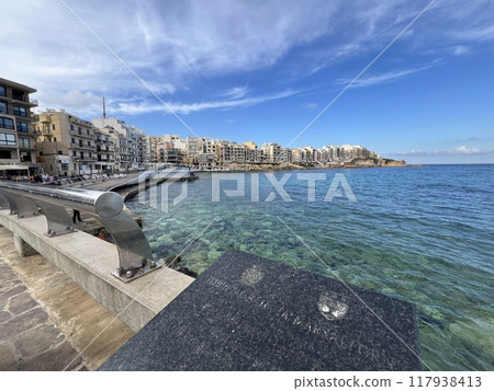 View of the promenade in Marsalforn Bay  (Salt Pans) at Gozo, Malta at sunny day with some clouds 117938413
