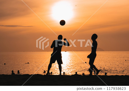 Silhouettes of Asian men playing beach soccer on beach by the sea at sunset Silhouettes of Asian men playing beach soccer on beach by the sea at sunset 117938623