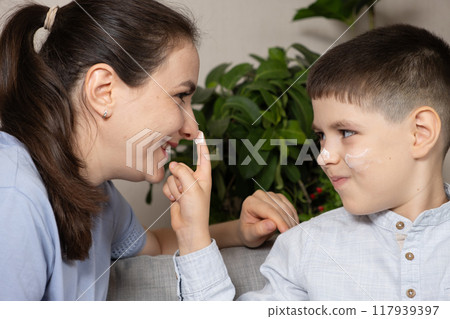 Mom and son apply cosmetic cream to their faces. Skin care and prevention 117939397