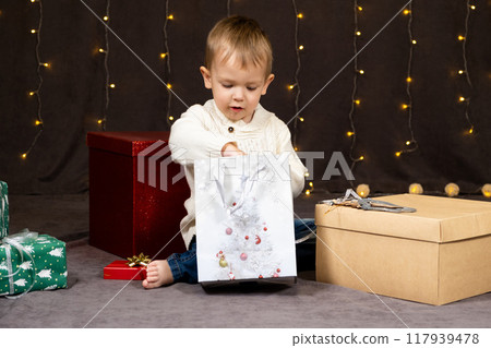 Little two-year-old boy opens Christmas gifts at home 117939478