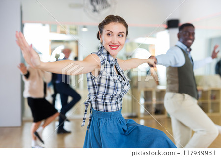 Cheerful female practicing lindy hop in pair with man 117939931
