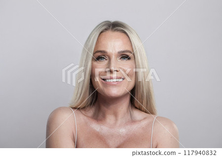 Happy blonde middle aged mature woman looking at camera on white background. Mature lady portrait Happy blonde middle aged mature woman looking at camera on white background. Mature lady portrait 117940832