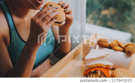 Binge eating disorder concept with woman eating fast food burger, fired chicken , donuts and desserts 117941015