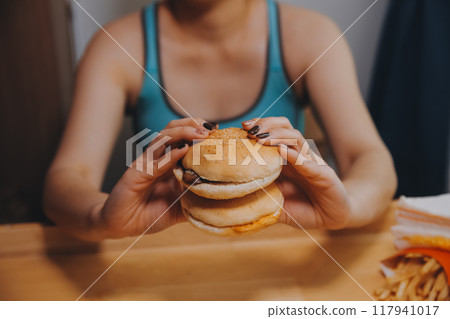 Binge eating disorder concept with woman eating fast food burger, fired chicken , donuts and desserts 117941017
