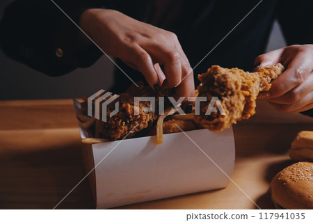 close up focus woman hand hold fried chicken for eat,girl with fast food concept close up focus woman hand hold fried chicken for eat,girl with fast food concept 117941035