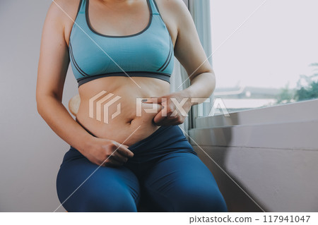 fat woman, fat belly, chubby, obese woman hand holding excessive belly fat with measure tape, woman diet lifestyle concept 117941047