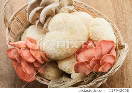 A wicker basket displaying various exotic mushrooms including lion's mane and pink oyster mushrooms. A wicker basket displaying various exotic mushrooms including lion's mane and pink oyster mushrooms. 117942008