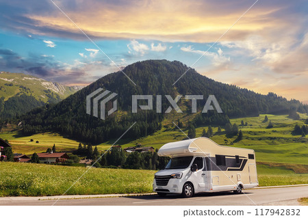 Scenic view big modern white family rv camper van vehicle drive Europe highway road alpine mountain cloud in summer day. Rving motorhome lifestyle travel adventure tourism trip Alps journey concept Scenic view big modern white family rv camper van vehicle drive Europe highway road alpine mountain cloud in summer day. Rving motorhome lifestyle travel adventure tourism trip Alps journey concept 117942832