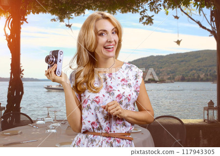 Woman on the beach with vintage photo camera. Sea landscape in the background. 117943305