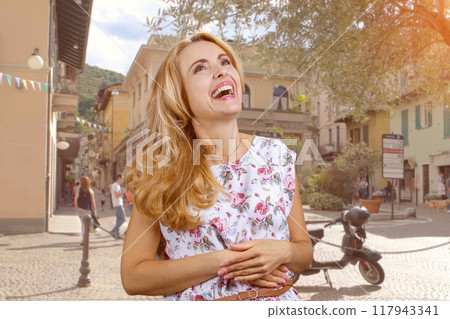Cheerful happy caucasian mature woman laughing outdoors. City street in the background. Cheerful happy caucasian mature woman laughing outdoors. City street in the background. 117943341