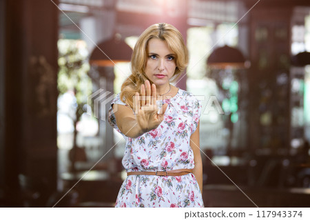 Portrait of sad negative woman show her palm as sign of prohibition. Restaurant interior in the background. Portrait of sad negative woman show her palm as sign of prohibition. Restaurant interior in the background. 117943374