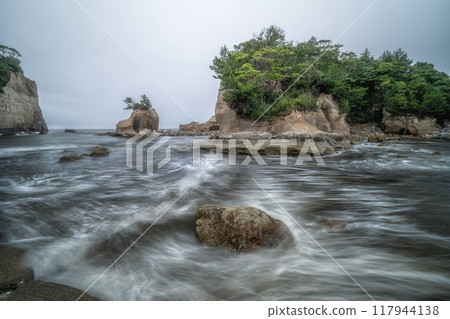 A small island and rough waves on a cloudy day 117944138