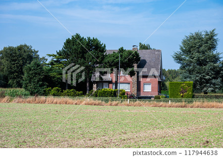 Cultivated vegetables on dry soil and farmhouse, Ternat, Belgium 117944638